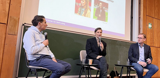 Laura Wontorra sitzt im Hörsaal und hält ein Mikro in der Hand