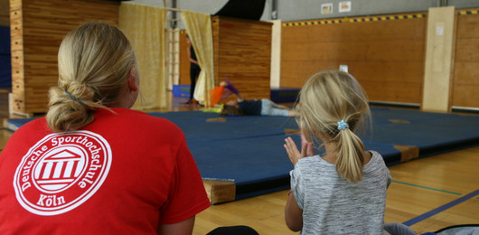 Betreuerin und Kind von hinten in einer Turnhalle